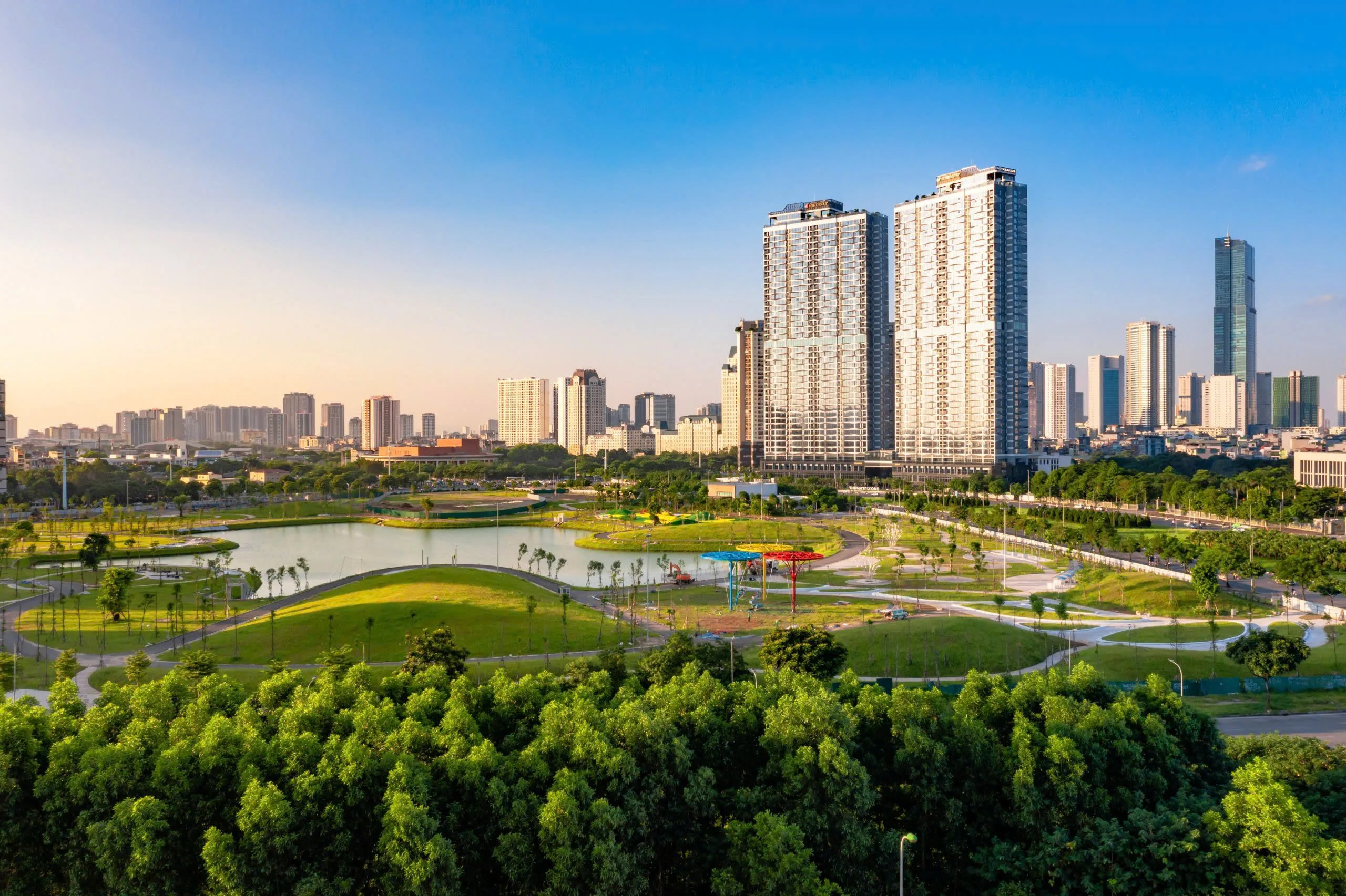 Công viên cây xanh ven sông với các tòa nhà cao tầng và tháp Landmark 81 phía xa
